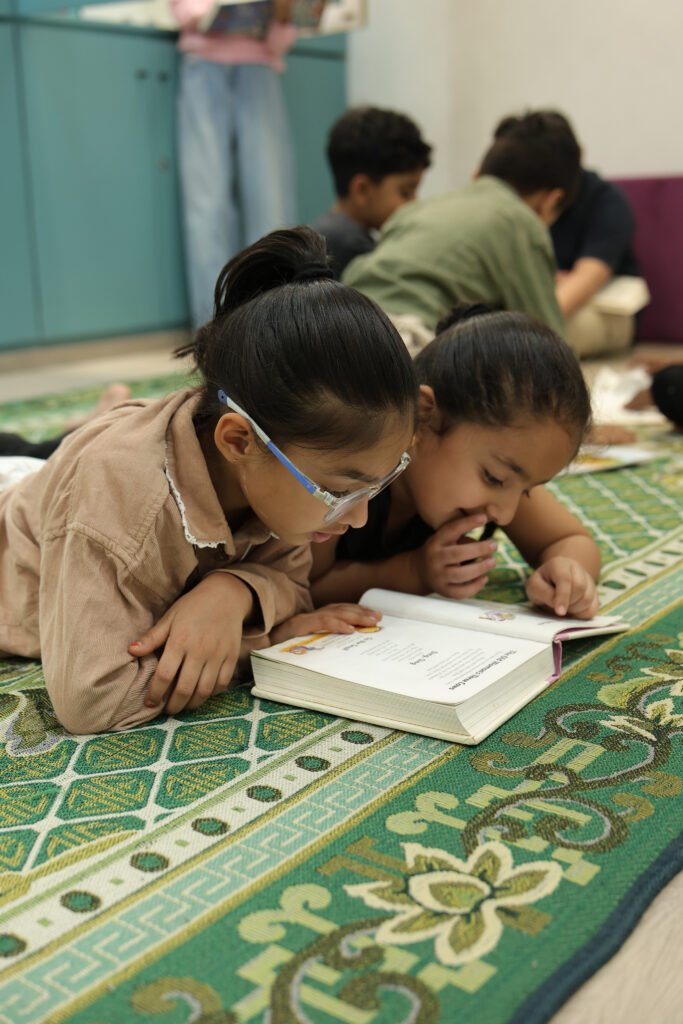 Children engrossed in reading a book at Zack's library room